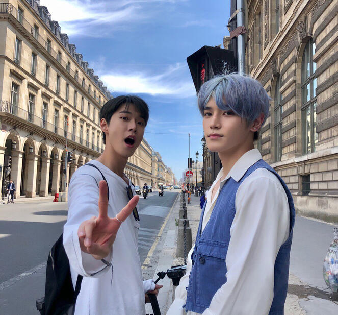 nct's doyoung and taeyong posing for a photo on the streets of paris